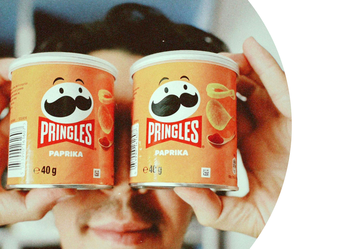 A man looking into two tubs of pringles.